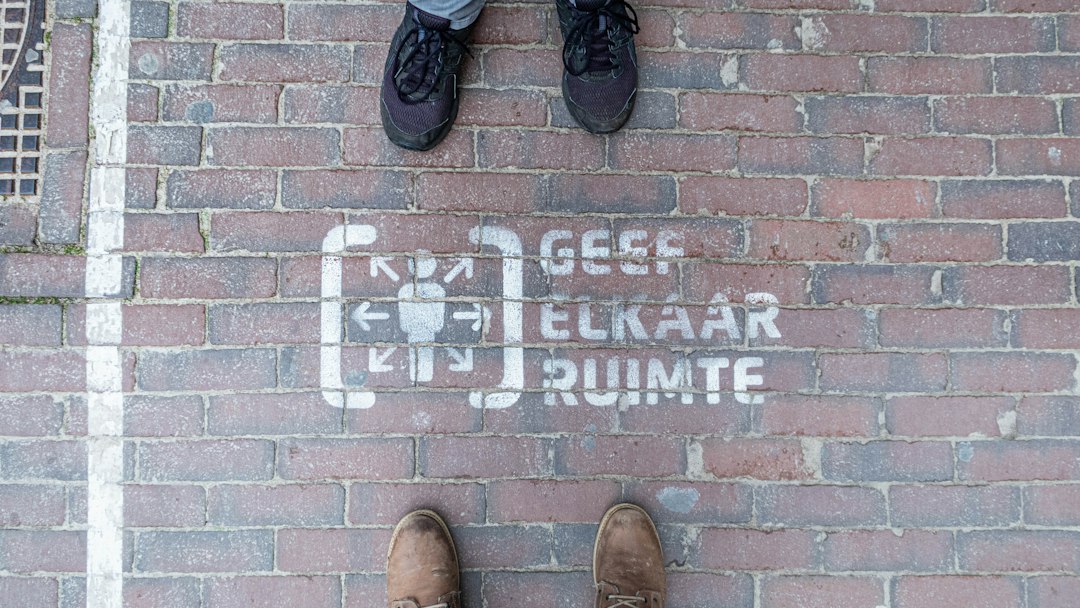 Give echother space sign on the ground in the city centre of Assen